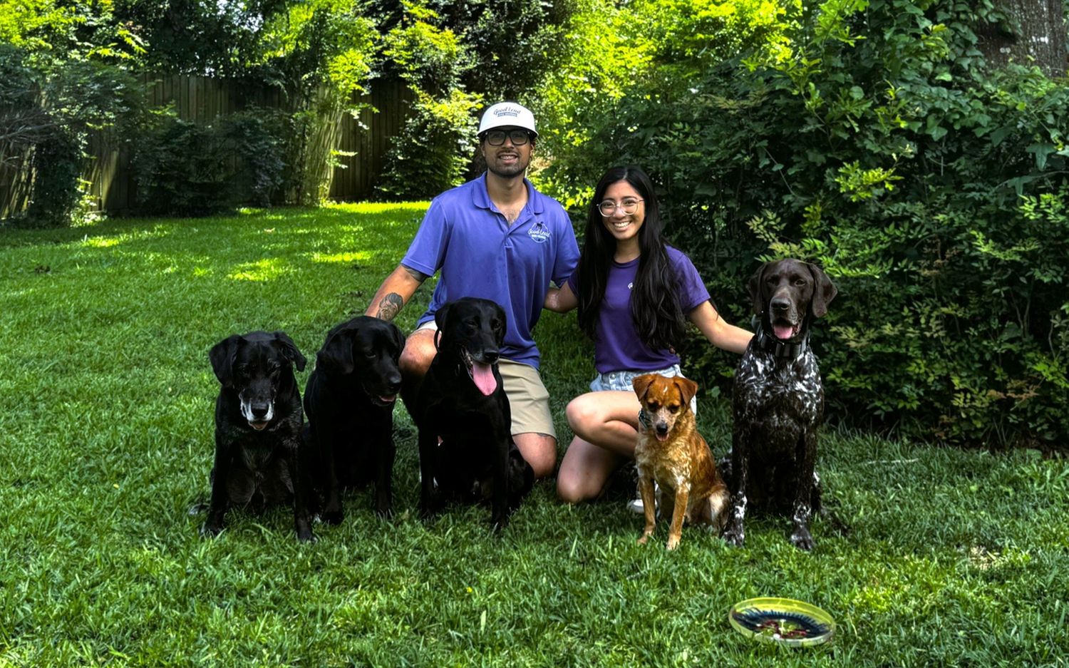 The Good Lead Dog Training team with a group of trained dogs on a green Houston lawn